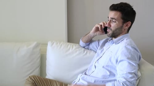 Man Talking on Phone While Sitting on Couch