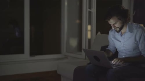 Man Working on Laptop at Night