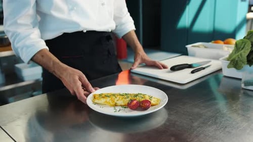 Professional restaurant kitchen, close-up: The chef serves an omelette