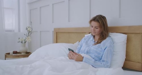 Woman Relaxing in Bed Using Her Phone