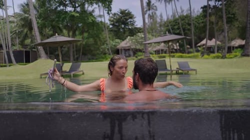 Couple Relaxing and Taking Selfies in Tropical Pool