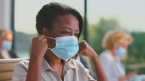 Black woman putting on face mask