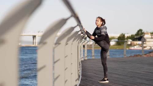 Woman Stretching Legs by Urban Waterfront