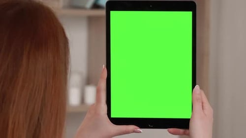 Close up shot of hands holding a tablet computer with green mock up screen.