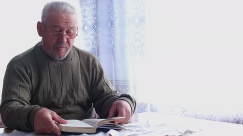 Senior Man Reading Book at Table