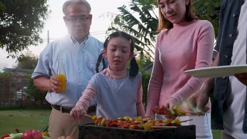 Happy Asian family having a barbecue-BBQ party together in the garden at home.
