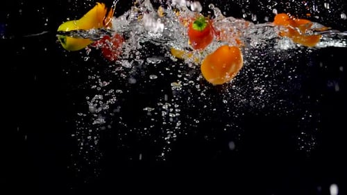 Colorful Peppers Falling into Water in Slow Motion