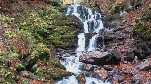 Narrow Stream Falling Down Mountain Slope in Autumn Forest