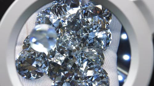 Hand Holds Diamonds Under Magnifying Glass