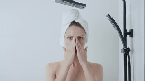Woman Applying Cream to Face in Bathroom