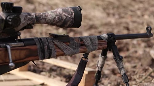 Camouflage Long Gun Resting Outdoors on Tripod