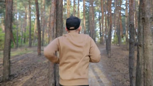 Back View of the Man Running in the Wood