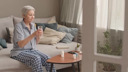 Senior Woman Taking Medication with Water