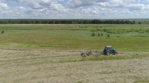 Trator com Rake Tedders no campo agrícola