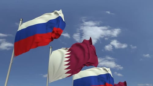 Waving Flags of Qatar and Russia Against Blue Sky