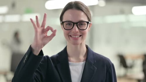 Smiling Woman Gives Ok Sign in Office Setting