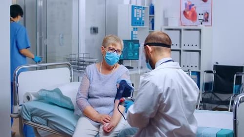 Doctor Checking Senior Woman's Blood Pressure in Hospital