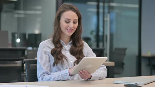 Young Woman Using Tablet at Desk in Modern Office