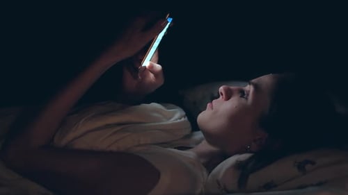 Woman Lies in Bed at Night Using Cellphone