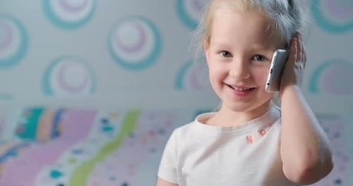 Little Girl Chatting on Smartphone Indoors