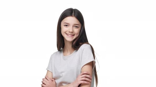 Portrait d'une jolie femme modeste de 18 ans souriante et posant avec les bras croisés et le regard timide