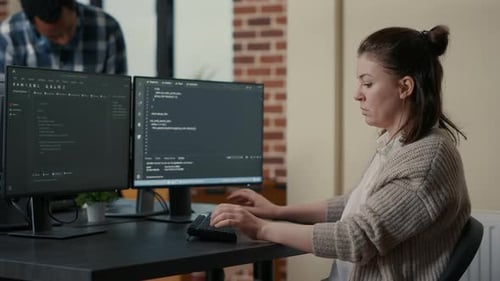 Portrait of Focused Programer Writing Code Looking at Multiple Computer Screens