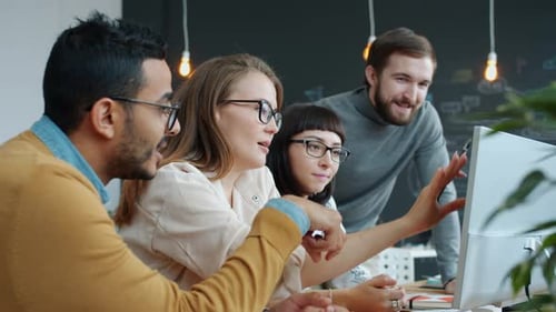Zeitlupe einer multiethnischen Gruppe von Menschen, die im Büro sprechen und auf den Computerbildschirm zeigen