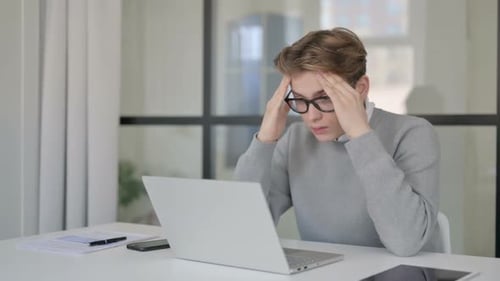 Young Man Having Headache While Working on Laptop in Modern Office