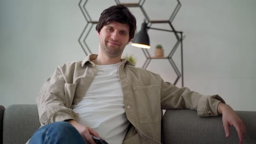 Man Relaxing on Couch Holding TV Remote