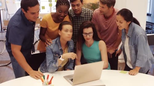 Team Collaborating Around Laptop in Modern Office