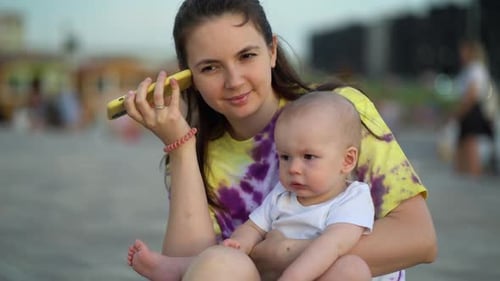 Mother Holding Baby While Talking on Phone
