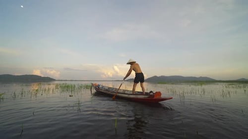Silhouette Fisherman casting or throwing a net for catching freshwater fish in nature lake