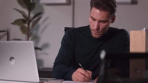 Man Writing at Desk in Office
