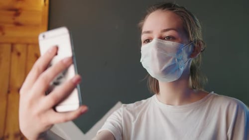 Young Adult Waves During a Video Call With Mask