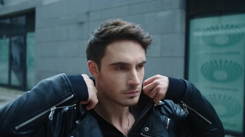 Retrato de un hombre joven caminando por la calle. Hombre guapo corrigiendo capucha