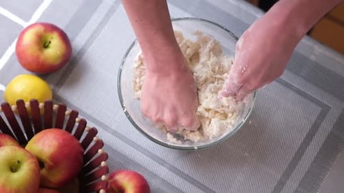 Hands Mixing Dough with Apples on Table