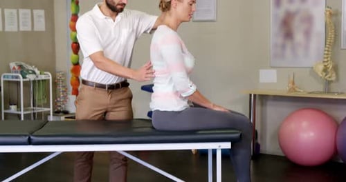 Männlicher Physiotherapeut gibt einer Patientin Rückenmassage