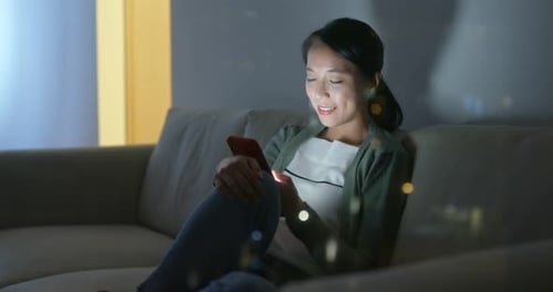 Woman Relaxing on Couch Using Smartphone at Night