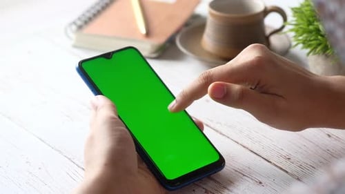 Rear View of Women's Hand Using Smart Phone on Office Desk