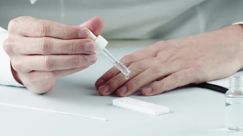 Hands with Dropper Testing Fluid in Lab