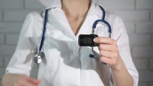 Healthcare Professional Holding Pulse Oximeter in Clinic