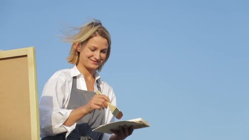 Woman Painting Outdoors with Brush and Palette