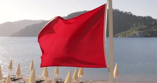 Vibrant Red Flag Blowing on a Beach