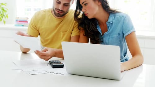 Couple Review Finances with Laptop at Home