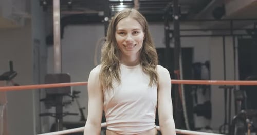 Woman Smiles and Waves in Boxing Ring with Gloves
