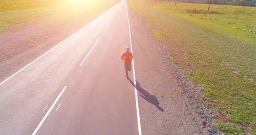Low Altitude Flight in Front of Sporty Man at Perfect Asphalt Road