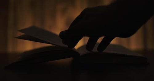 Hand Turning Pages of Book in Silhouette