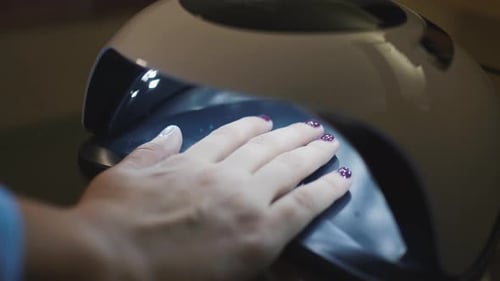 Close Up of Woman Hand in UV or Led Lamp Drying Gel Polish on Her Nails