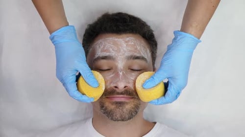 Man Receiving Facial Cleansing Treatment With Sponges