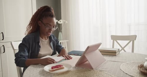 Woman Chatting Via Tablet At Her Kitchen Table